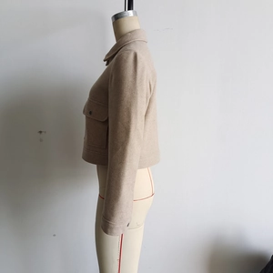 Détails de la veste courte en laine kaki montrant la poche latérale et les boutons aux poignets