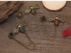 Macro shot of vintage bronze bee brooches with rhinestones and elegant double chains