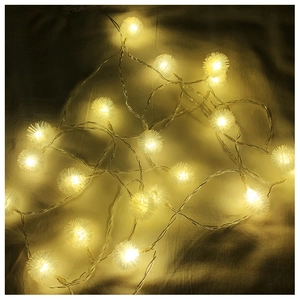 Detail view of warm white dandelion pom-pom LED fairy lights on a textured cloth background