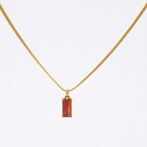 Detail of 18K gold snake chain featuring a square red gemstone pendant with 4-prong setting