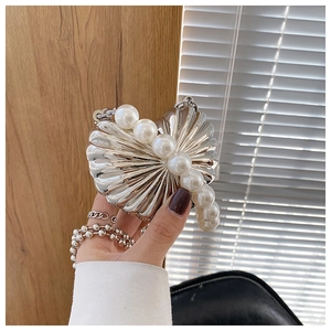 Detail of silver shell box bag featuring white faux pearl handle and metal chain strap
