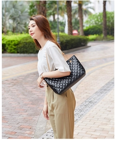 Outdoor street view of a woman wearing a black quilted tote bag with metal chain strap