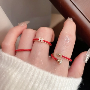 Close-up of minimalist snake red cord rings with gold H-mark and nail design details