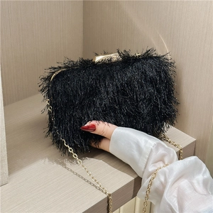 Close-up of black fringe evening bag featuring elegant gold chain strap and metal clasp