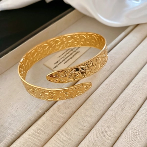 Detailed macro view of the gold hollow embossed floral pattern on this open cuff bracelet