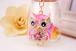 Detailed close-up of a golden owl keychain with pink rhinestones and enamel accents