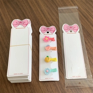 Pink bow cardboard packaging for hair clips with four colorful kids floral barrettes