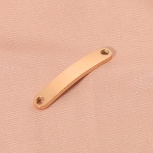 Detailed view of curved rose gold geometric metal strip connector with dual holes