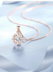 Macro detail of rose gold sunflower pendant with a central dancing stone and cubic zirconia