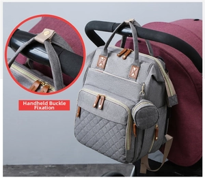 Detail showing snap-button handle closure on grey quilted diaper bag hanging on a stroller