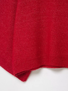 Detailed close-up of vibrant red knit sweater featuring ribbed hem and wool texture