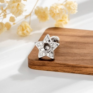 Minimalist silver star stud earring with small diamonds on a wooden coaster