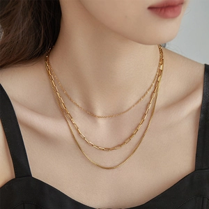 Three-layer stacked gold Cuban link chain necklace set on model with minimalist retro style