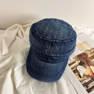 Detailed view of dark blue washed denim flat top cap with vintage texture and stitching