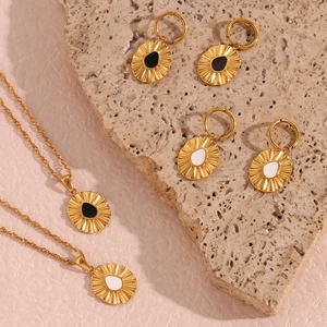Detailed view of gold sunflower teardrop earrings and necklaces on a natural stone background
