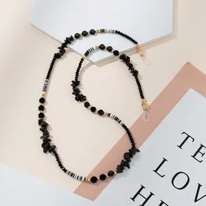 Detail of eyewear chain featuring black stones, golden beads and striped tube accents