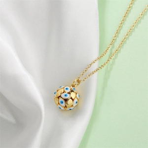 Close-up of golden sphere pendant with blue eye patterns on soft white silk fabric