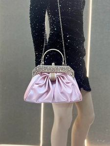 Detail of pink satin evening bag with rhinestone clasp and bow handle shown on a model
