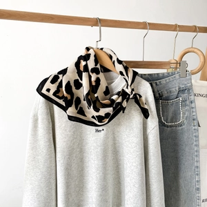 Detail eines Seidenschals mit Leopardenmuster kombiniert mit einem grauen Baumwoll-Sweatshirt