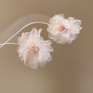 Close-up of pink fabric flower earrings featuring delicate beaded center detail