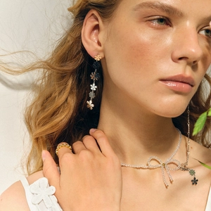 Détail de boucles d'oreilles marguerite en or 18k et collier perle portés par un modèle