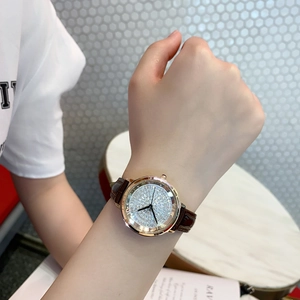 Close-up of rose gold watch with crystal-encrusted dial and brown leather strap