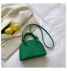 Detail of a bright green shell bag featuring V-shaped quilting and gold hardware accents
