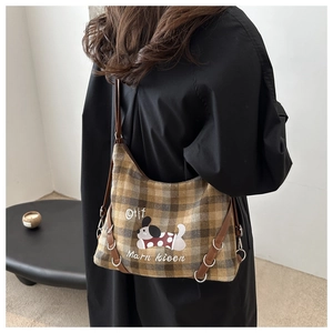 Detail of checkered canvas crossbody bag featuring dog illustration and brown leather strap