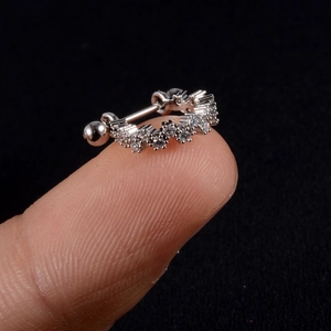 Macro shot of silver zircon earring with screw ball back held on fingertip for size