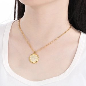 Macro detail of a golden necklace with a circular pendant encrusted with white cubic zirconia