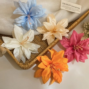 Detailed close-up of colorful silk lily hair clips in a rustic woven tray on white mesh