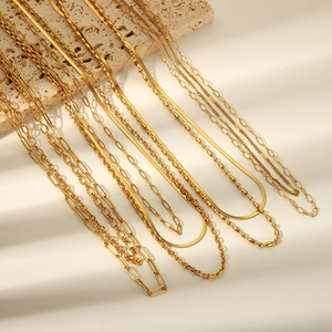 Detail showing multi-layer gold chain necklace set with flat snake and paperclip link designs