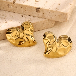 Detailed close-up of golden heart-shaped stud earrings with unique hammered metal texture