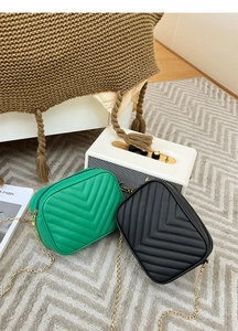 Detail of quilted cross-body bags in green and black with gold metal chain straps