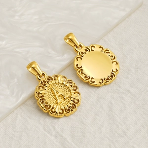 Gold letter A pendant with intricate embossed floral border on white marble background