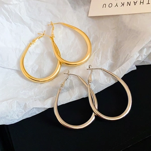 Detailed view of large minimalist oval drop earrings in both gold and silver metallic finishes