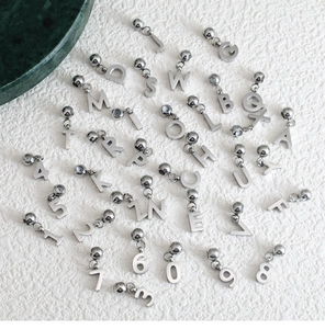 Macro shot of silver metal DIY alphabet and number pendants on white texture background
