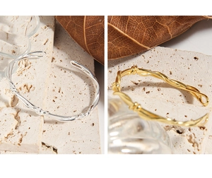 Detail of twisted woven S925 sterling silver cuff bracelets in gold and silver finishes