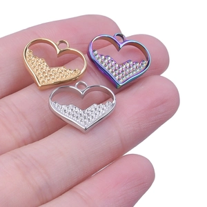 Close-up of heart-shaped hollow pendants in gold, silver, and rainbow steel finish