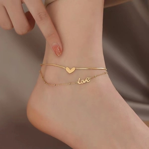 Bracelet de cheville double en acier doré avec pendentifs coeur et love sur modèle