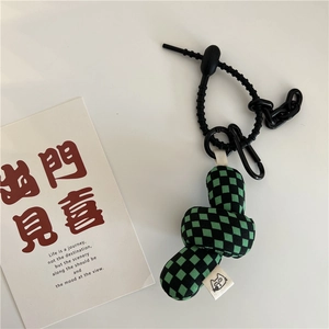 Detail of green and black checkered fabric charm with a black woven cord and hook