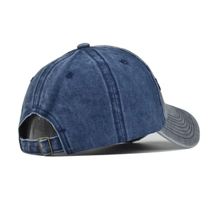 Detail view of denim baseball cap showing adjustable bronze metal buckle and stitching