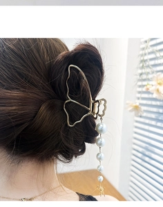 Detail shot of a golden butterfly hair claw with pearl tassels on a woman hair