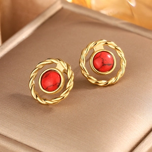 Close-up of vintage 18K gold earrings featuring red stone beads and braided textures