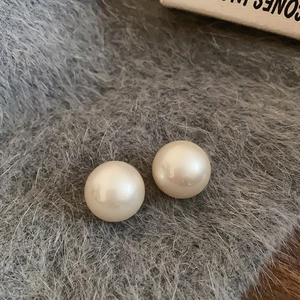 Vue macro de boucles d'oreilles perles rondes sur un fond de peluche gris doux et chic
