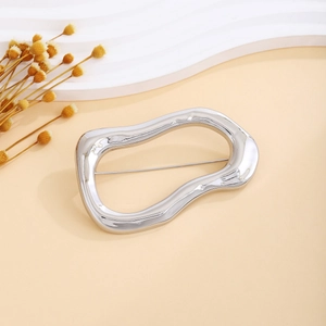 Detailed view of an irregular wavy oval silver brooch with a sleek polished finish