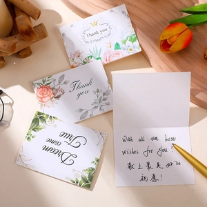 Set of four floral paper thank you cards with handwritten wishes on wooden background