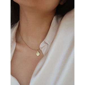Detailed view of vintage rose pendant necklace in gold finish on a white shirt