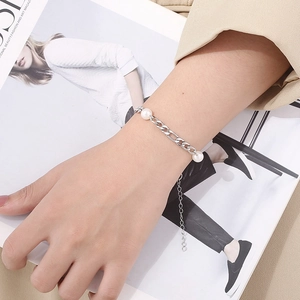 Detail of silver Figaro chain bracelet with white pearls and adjustable extender link