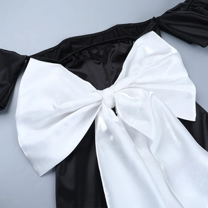 Détail d'un grand nœud en satin blanc sur une robe de soirée noire à épaules nues